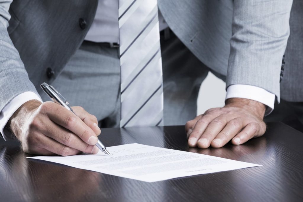 a man signing a document while standing