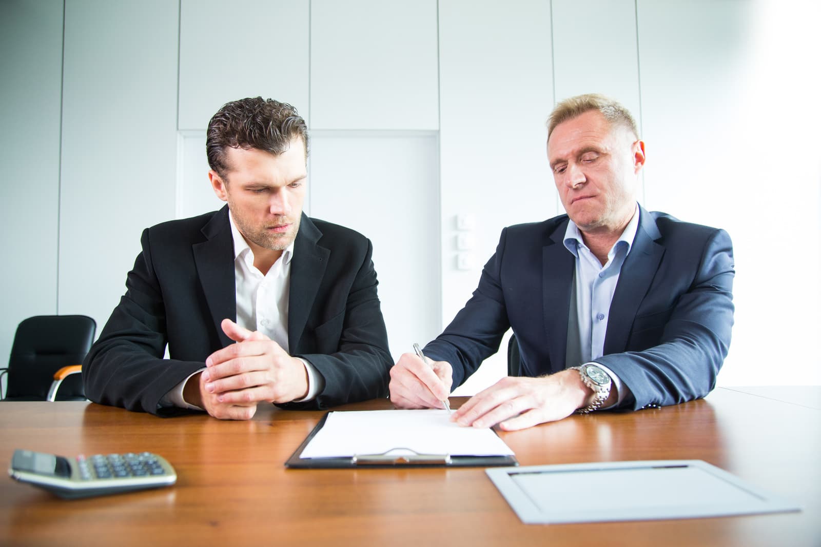 an image of two men discussing over a document