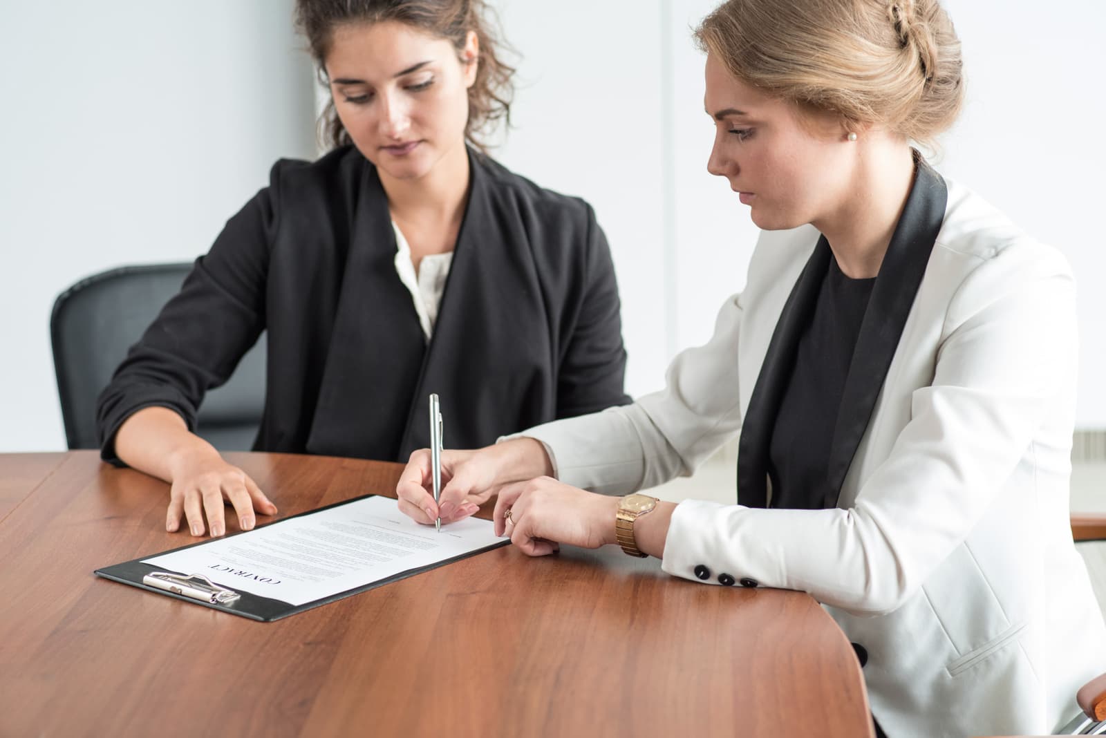 two women in suit with one of them writing a notary document